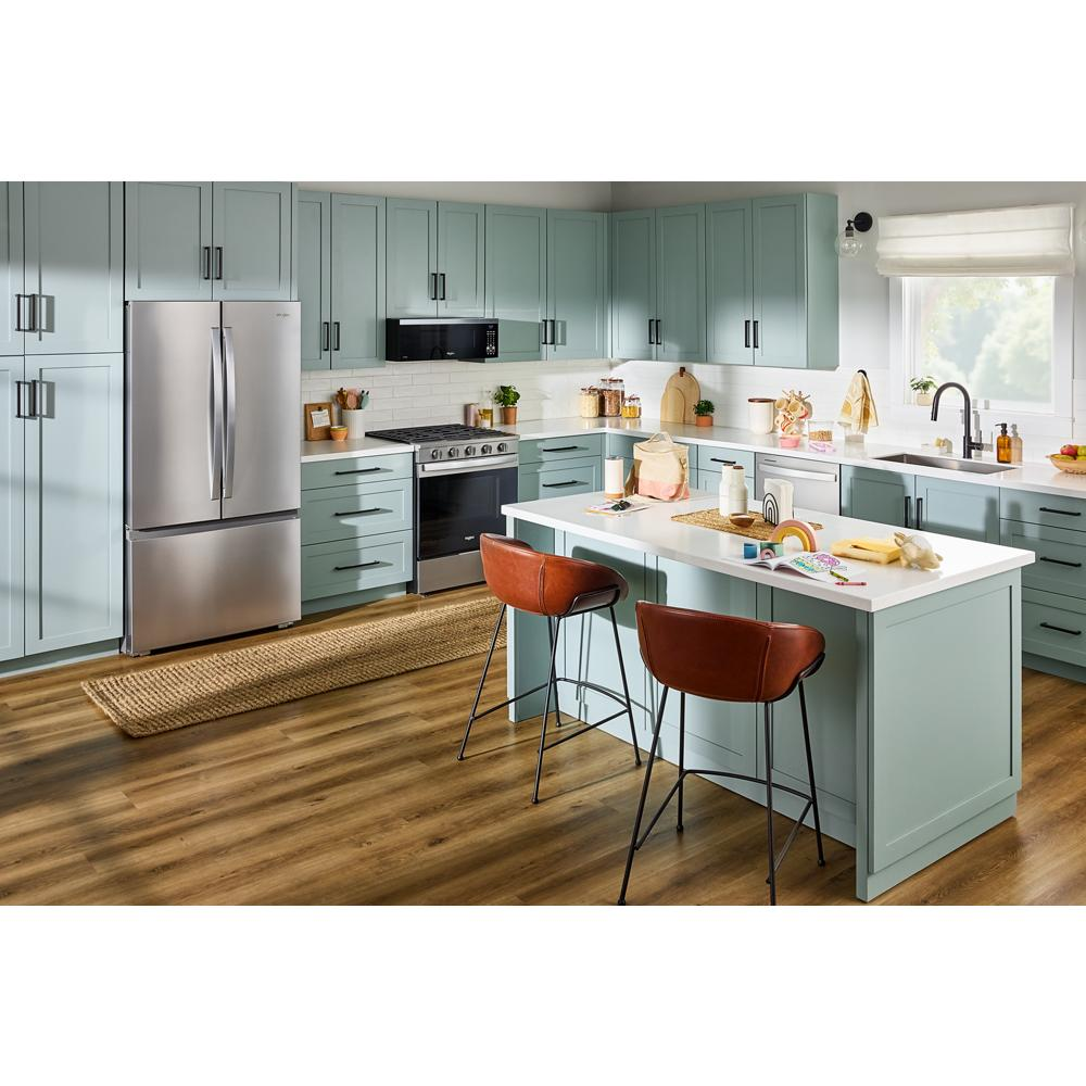 Modern kitchen with stainless steel bottom freezer refrigerator, green cabinets, white island, and wood flooring in home improvement setting