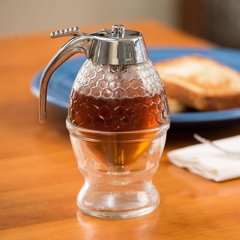 Glass honey and syrup dispenser with honeycomb pattern and metal lid in kitchenware and storage collections