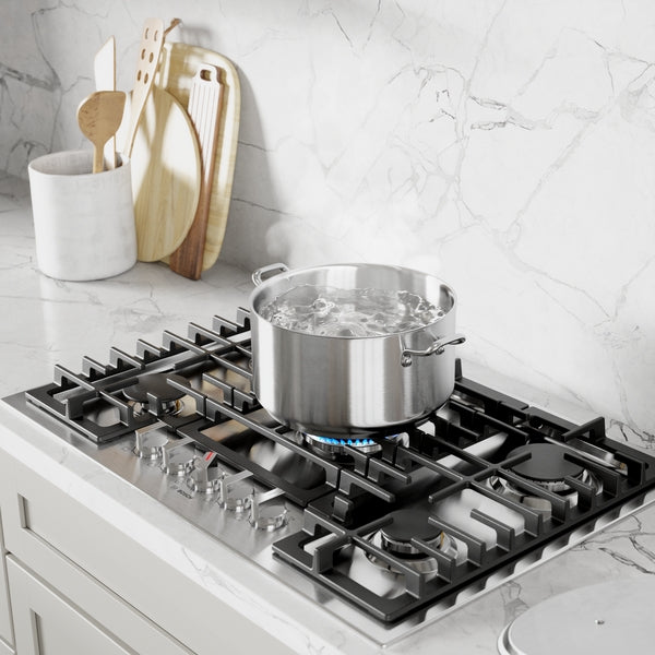 30-inch stainless steel gas cooktop with boiling water in pot and wooden utensils in marble kitchen setting