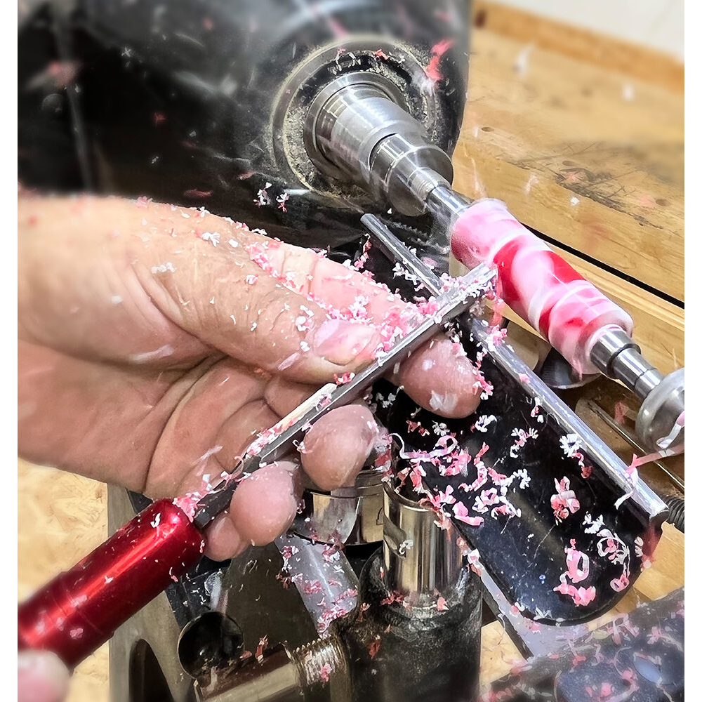 Hand shaping pink resin blank on lathe using red Sorby Micro Resin Pen Turning Set in woodworking tools collection under $100