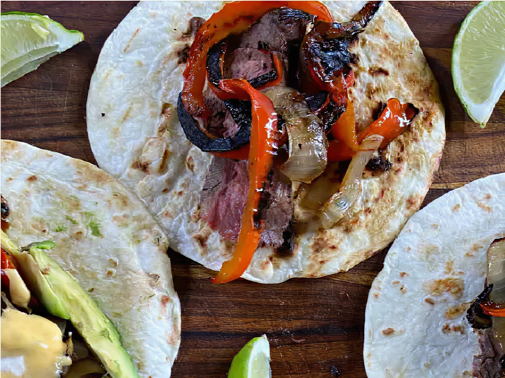 Grilled steak and charred red peppers with onions served on a lightly toasted flour tortilla with lime wedges on the side