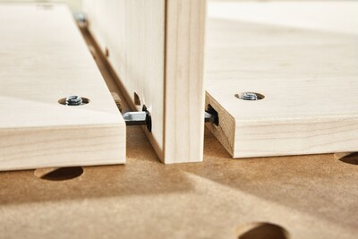 Close-up of central panel connector joining two light wood boards in woodworking tool accessories for home improvement projects