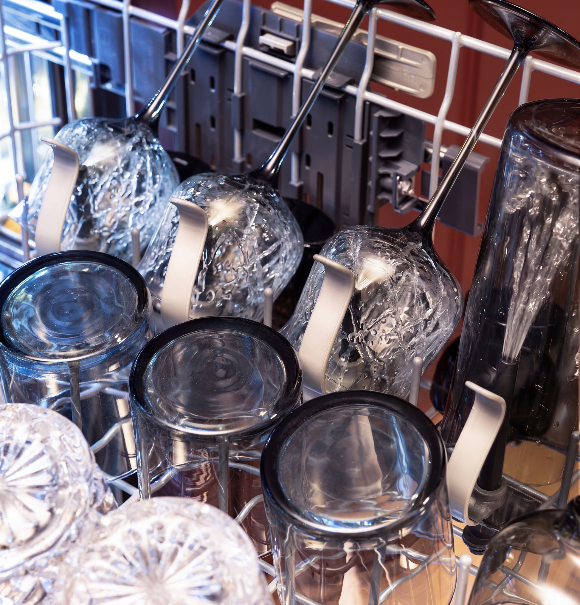 Inside fully integrated dishwasher showing clean glasses and utensils arranged in racks for drying in kitchen appliance setting
