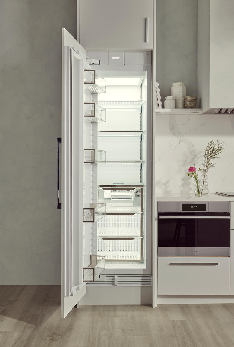 Open white upright freezer with adjustable clear shelves and transparent door bins, in modern kitchen setting