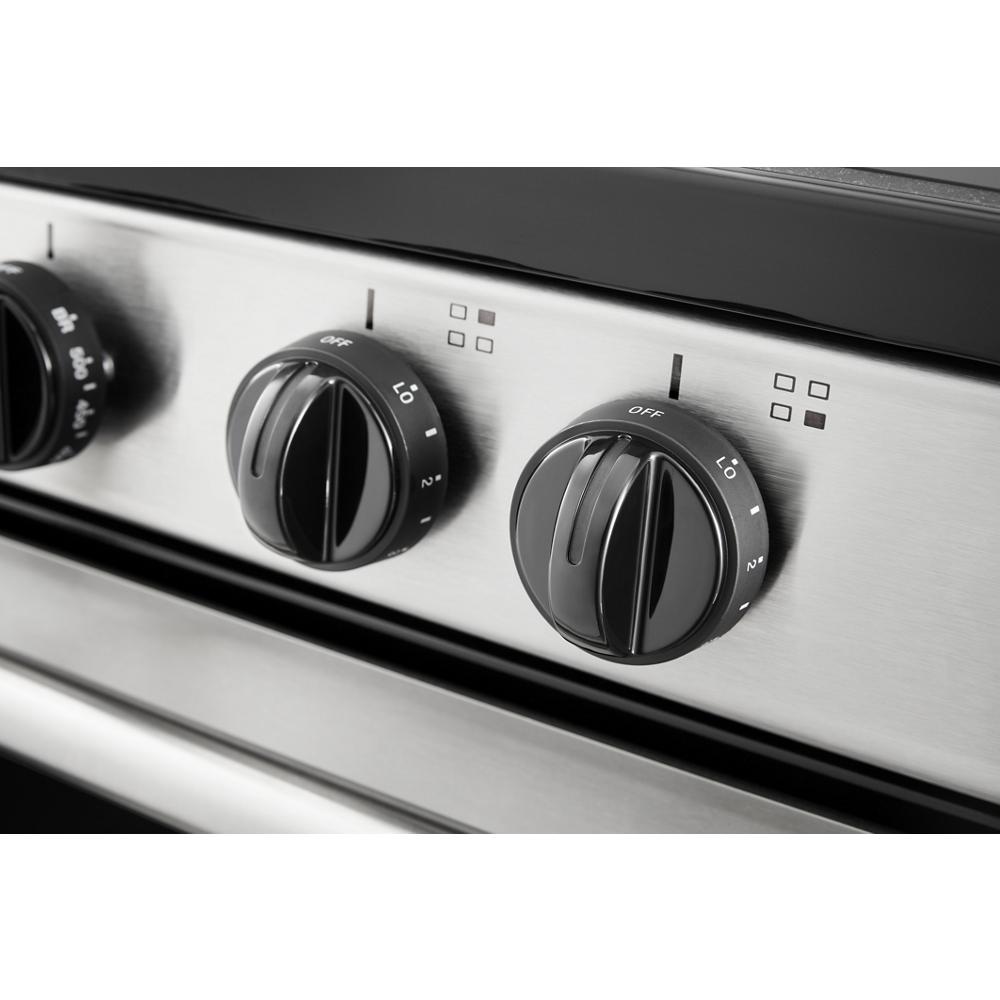 Close-up of black control knobs on stainless steel panel for electric range in kitchen appliance collection
