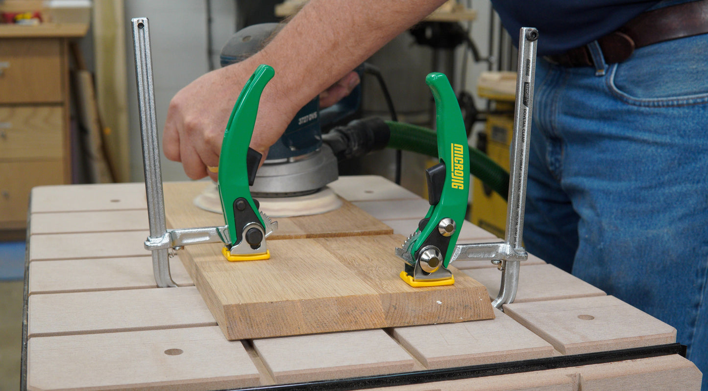 Green-handled Microjig MATCHFIT ratchet clamps holding wood on a workbench during a home improvement project