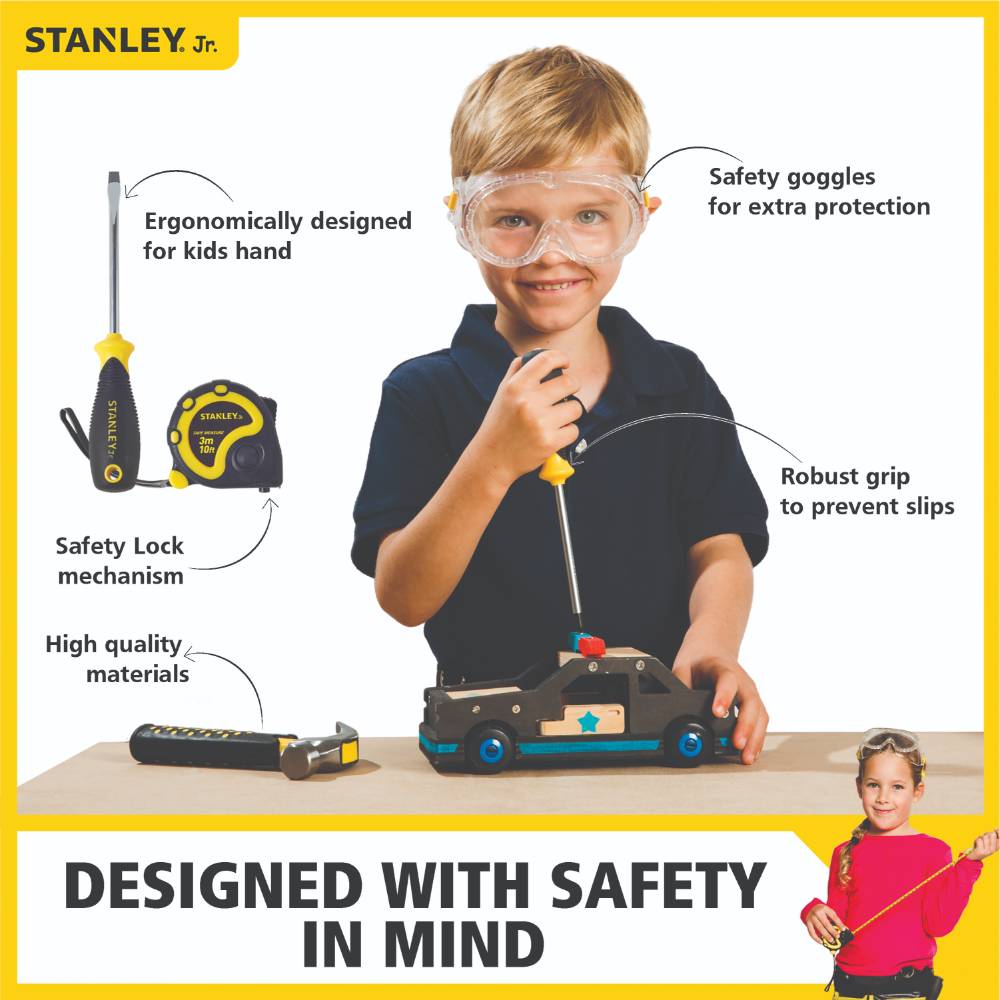 Boy playing with Stanley Jr 5-piece toolset including hammer, screwdrivers, tape measure, and safety goggles in Pretend Play Toys