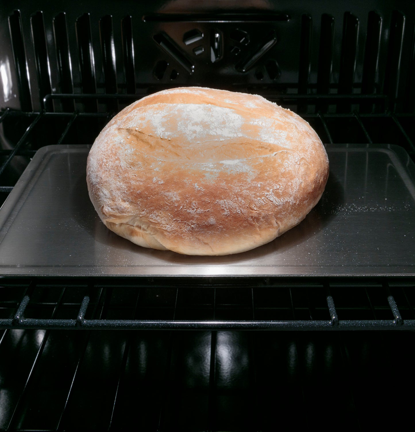 Loaf of bread baking on metal tray inside smart convection single wall oven from kitchen appliances collection