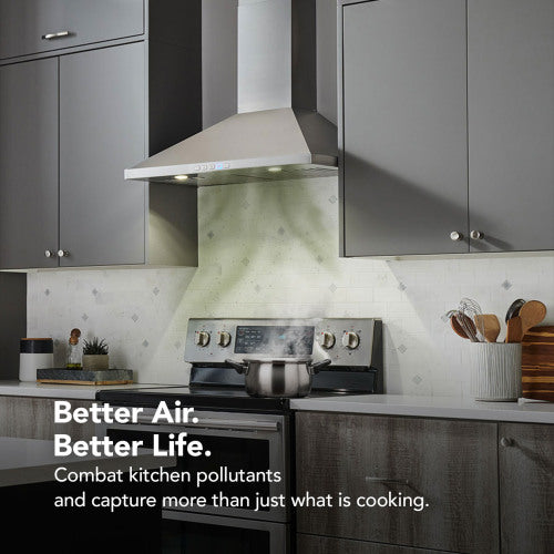 Modern stainless steel range hood installed above stove in kitchen with gray cabinets and cooking utensils nearby