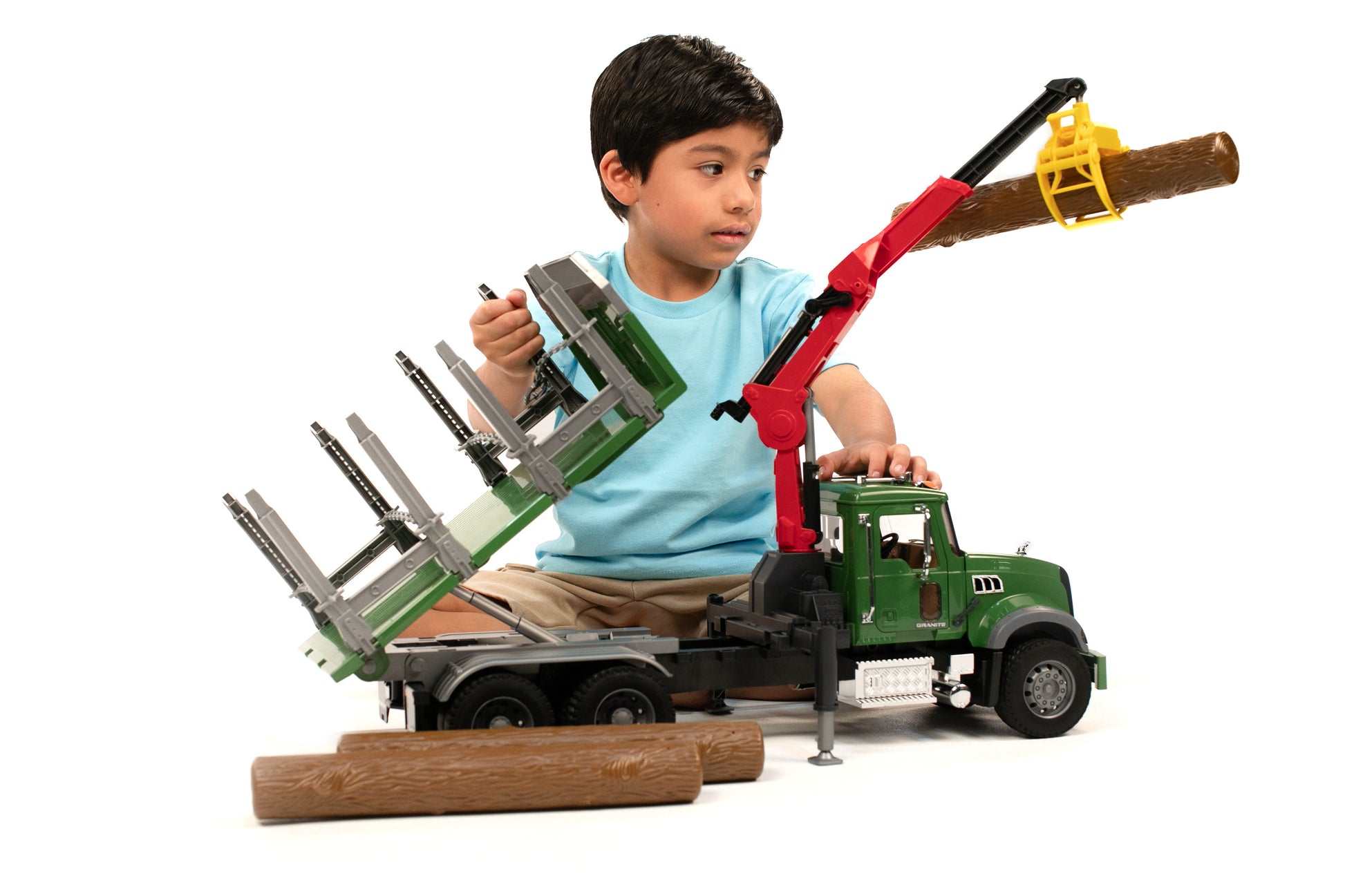 Child playing with green MACK timber truck toy featuring red loading crane lifting log in Toys & Games collection