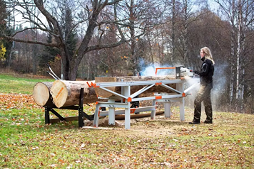 Metal portable sawmill with three log lifts cutting large timber outdoors in a wooded home improvement setting