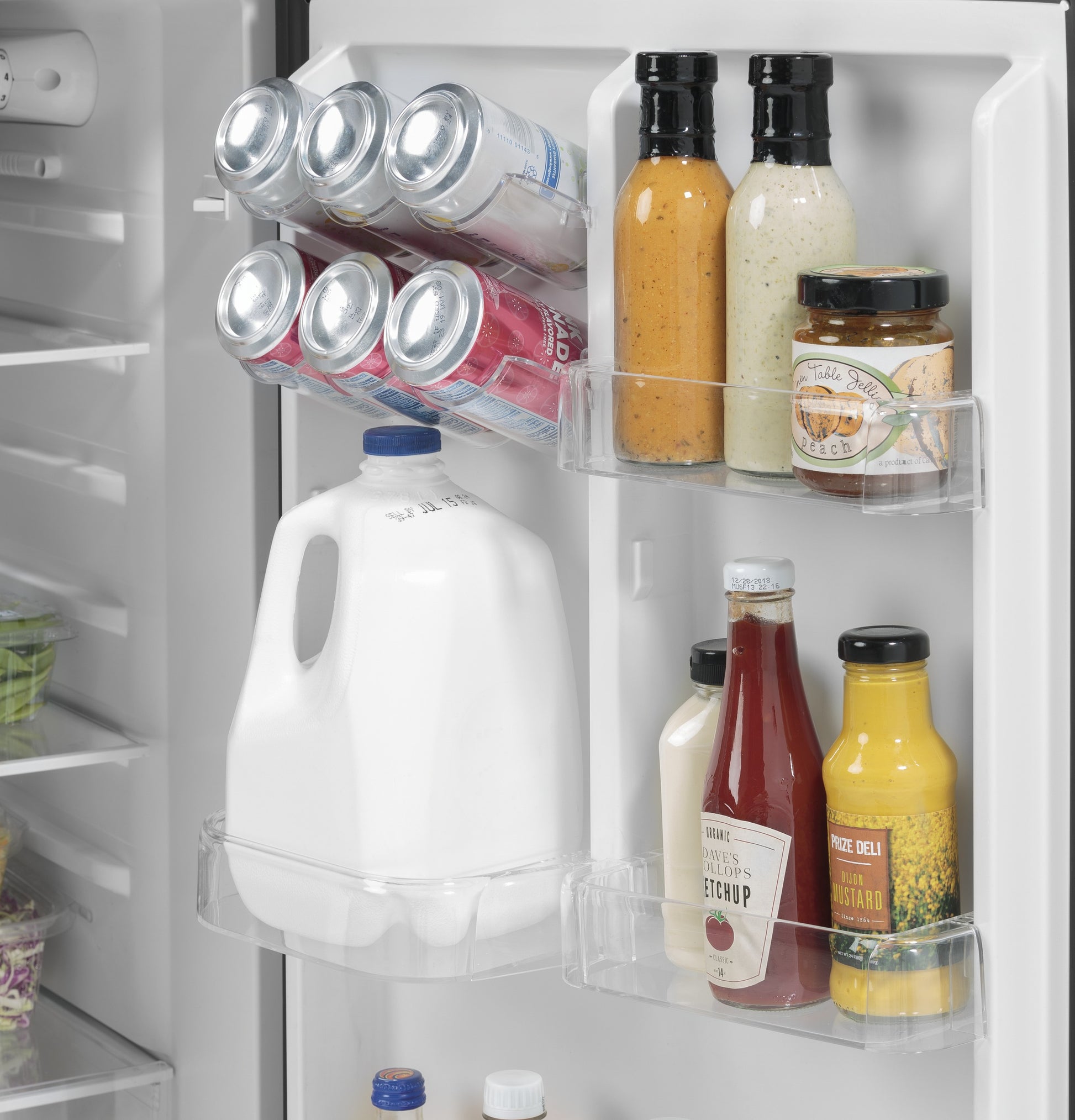 Clear refrigerator door shelves holding condiments, six cans, and a gallon of milk in a kitchen appliance setting