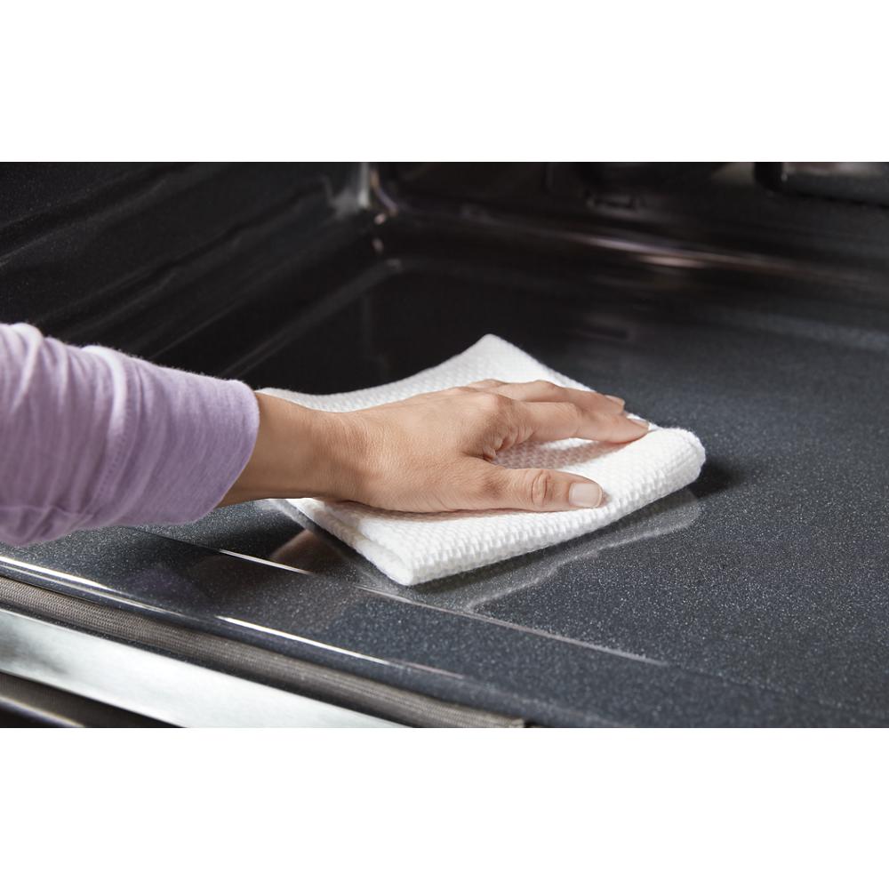 Hand wiping the interior surface of a dark combo wall oven from the Kitchen & Kitchenware collection