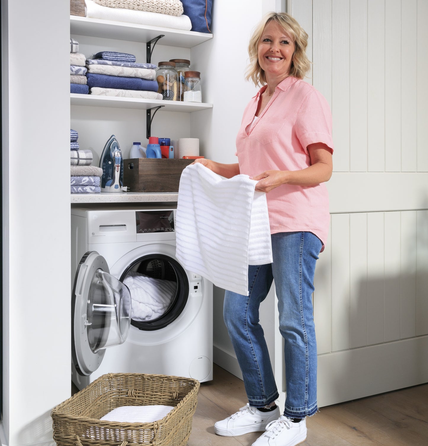 Woman standing in laundry room holding white towel near open front load washer from Washer/Dryer Combos collection
