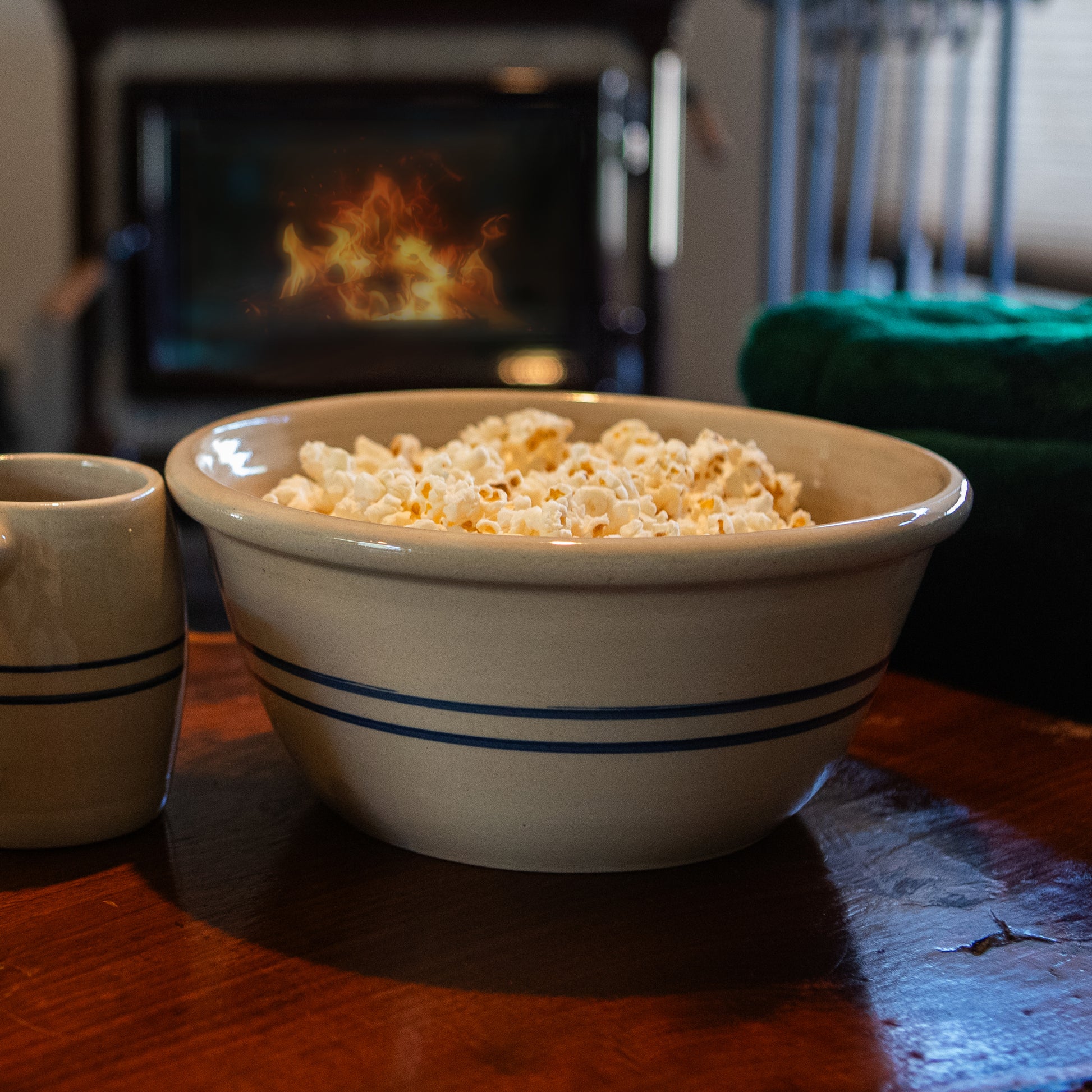 Cream-colored stoneware bowl with heritage blue stripes filled with popcorn on wooden table in kitchenware collection under $100
