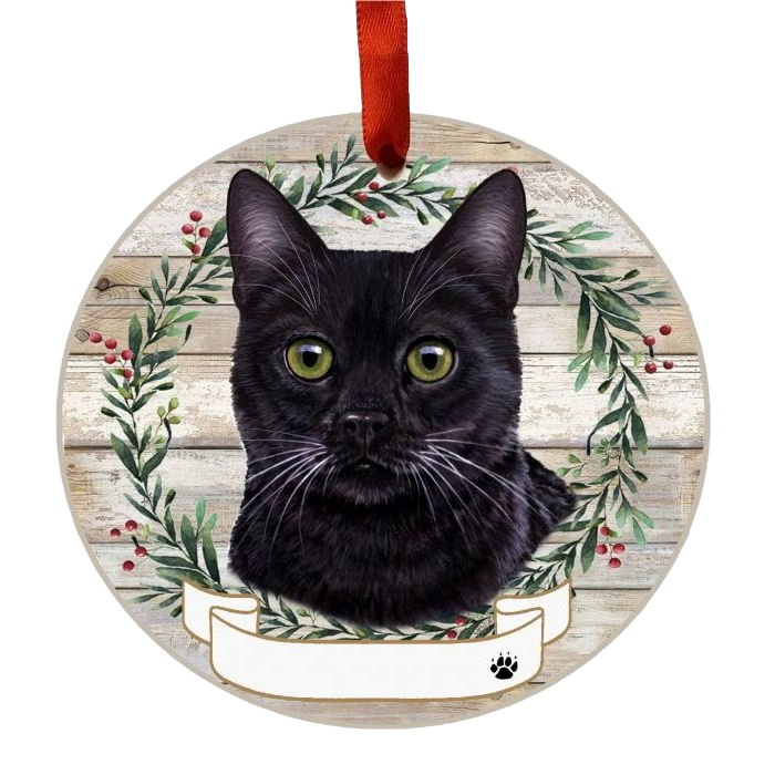 Round wooden ornament featuring a black cat face inside a festive wreath with red berries and hanging ribbon