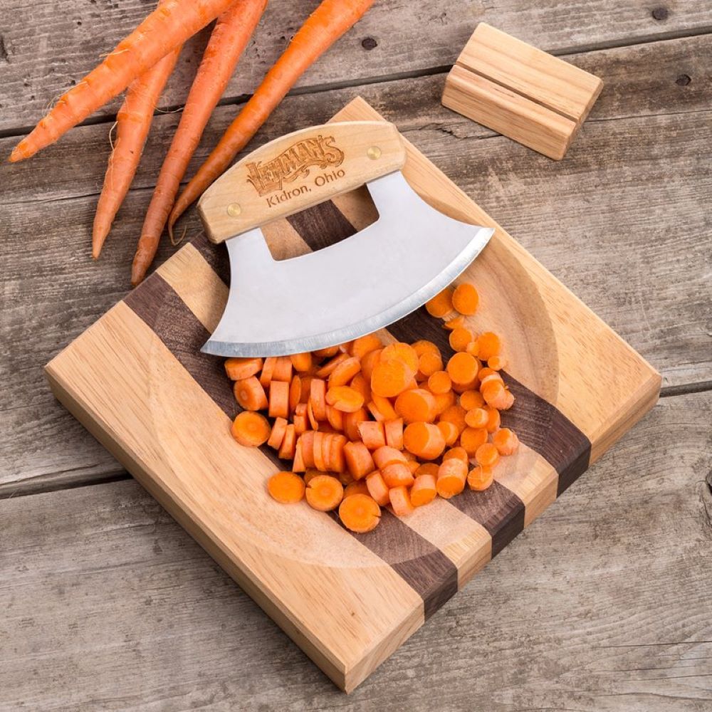 Half-moon ulu knife with wooden handle on striped wooden cutting board chopping fresh carrots in kitchenware collection