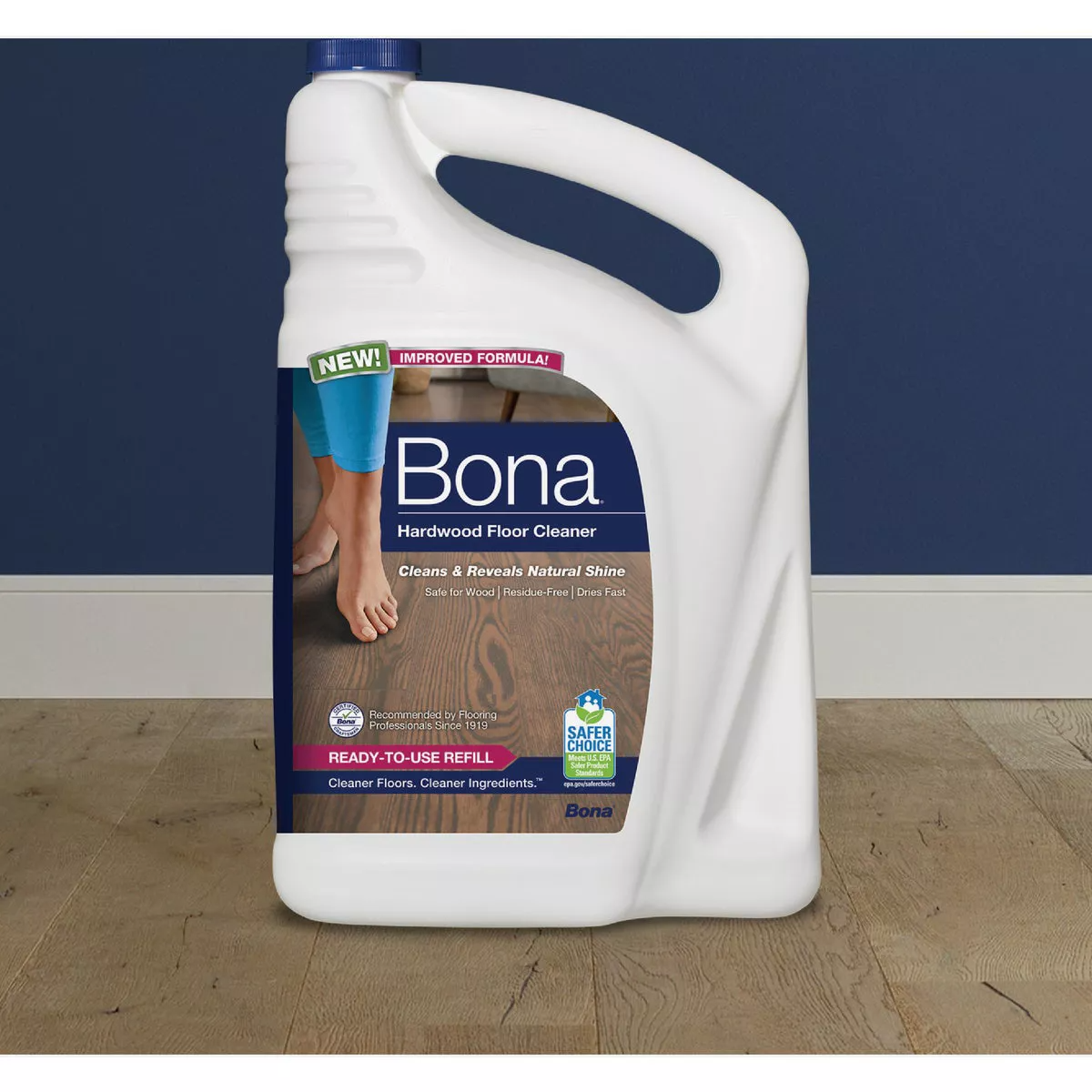 White jug with blue cap of hardwood floor cleaner showing label with bare feet on wood floor and usage claims