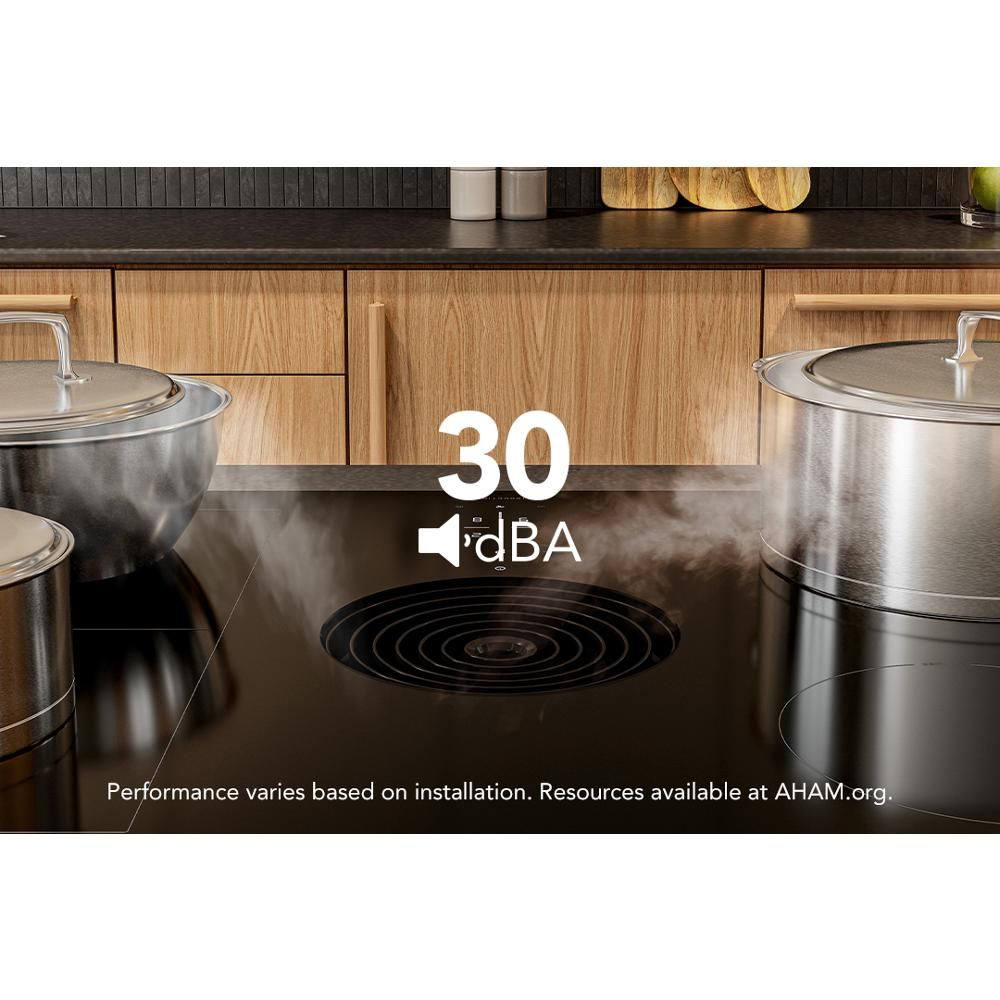 Black induction cooktop with downdraft vent quietly extracting steam while stainless steel cookware simmers