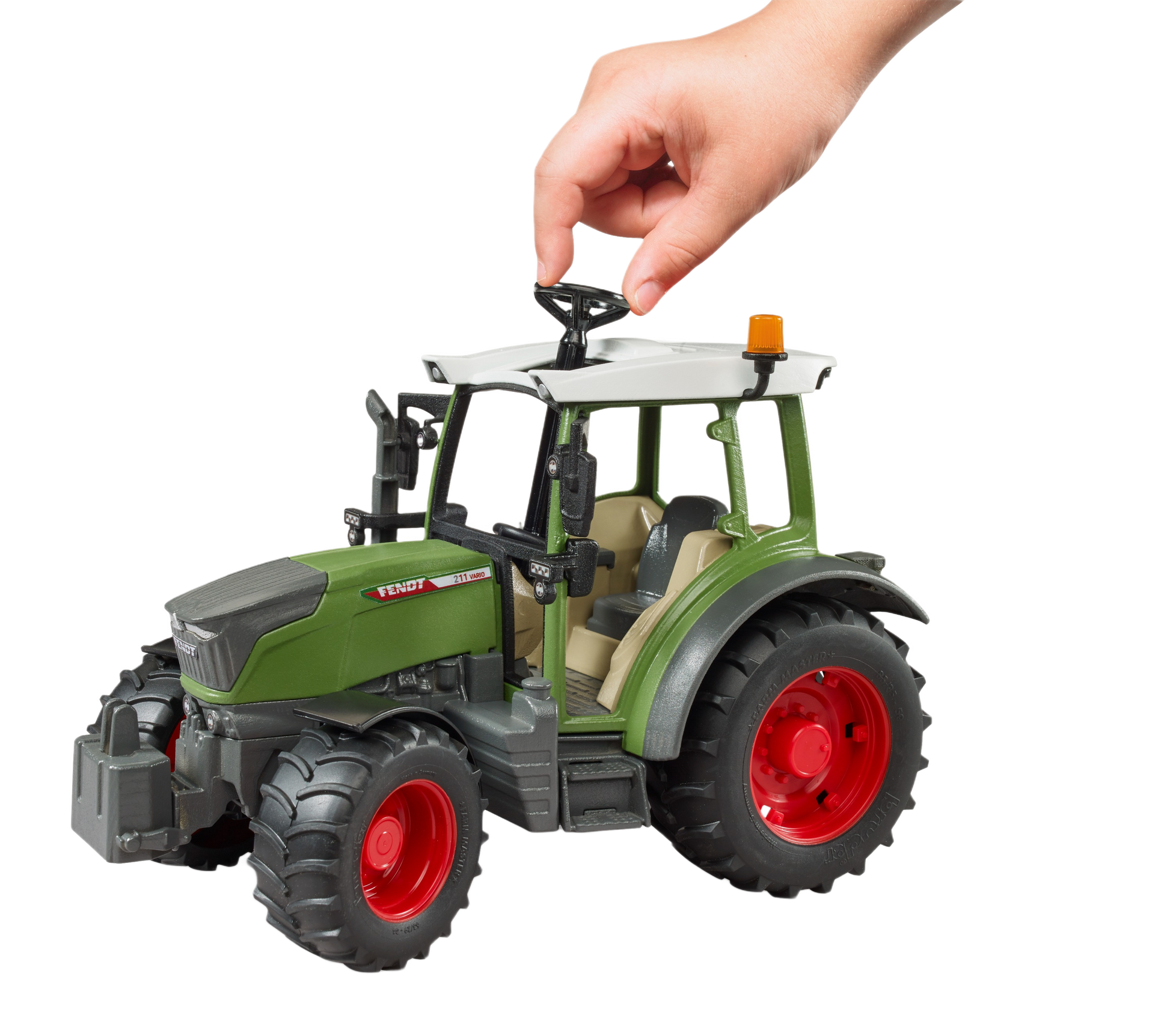 Hand turning the steering wheel of a green Bruder Fendt Vario 211 tractor model with red wheels for tools and home improvement fans