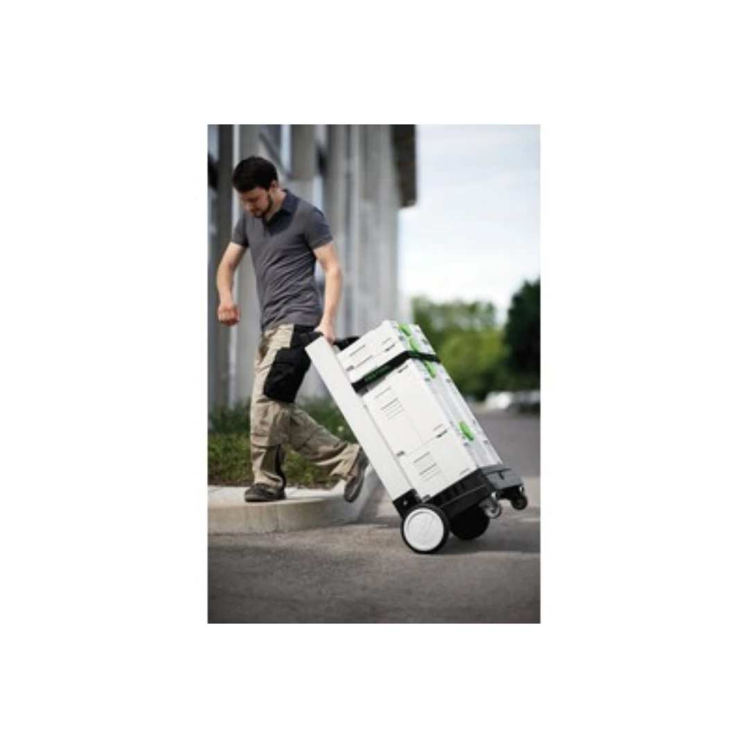 Man pulling white storage dolly with large wheels carrying stacked tool cases for jobsite and workshop use
