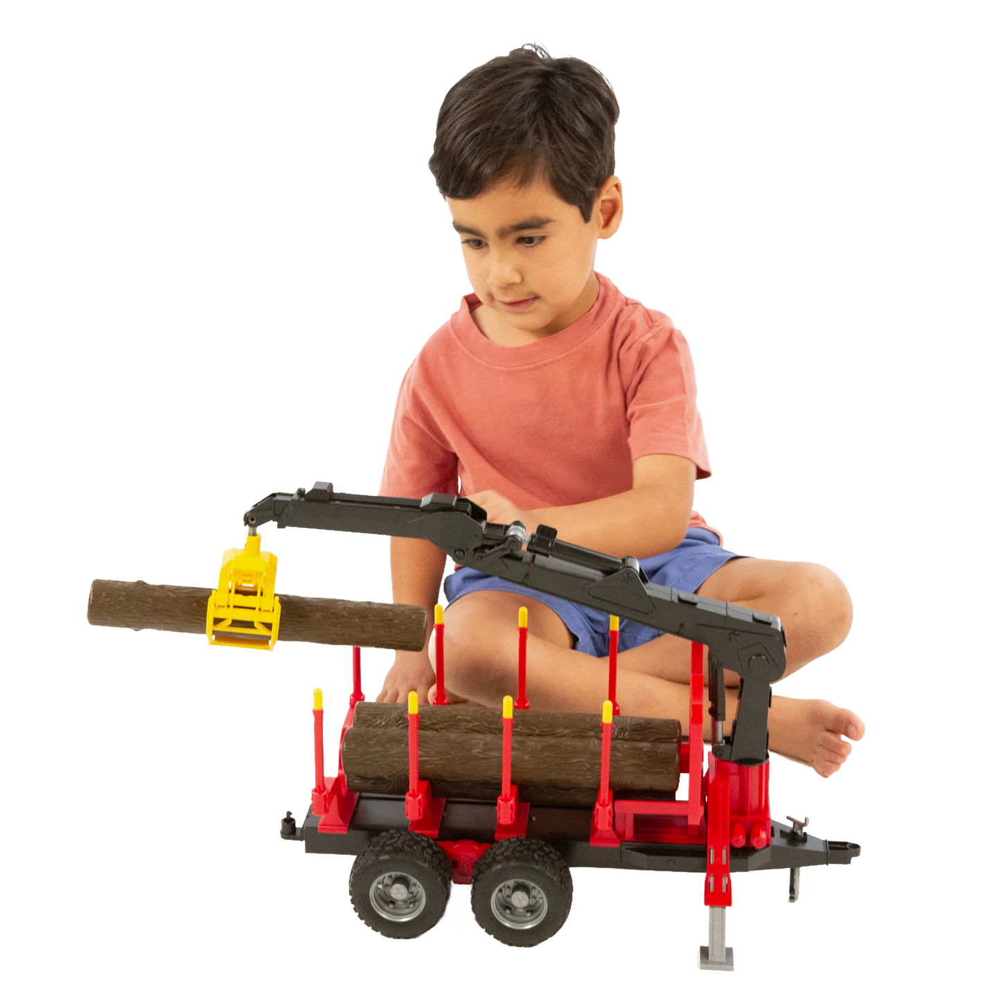 Child playing with red Bruder forestry trailer toy with black crane and yellow grapple lifting wooden log in Toys & Games collection