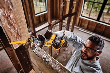 Man using DEWALT cordless one-handed reciprocating saw to cut wood framing in home renovation project