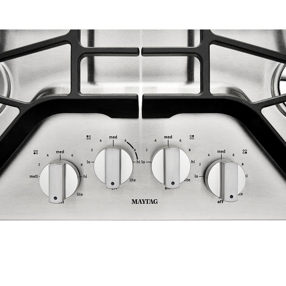 Close-up of stainless steel cooktop control panel with four round knobs and burner level markings from Kitchen & Kitchenware collection