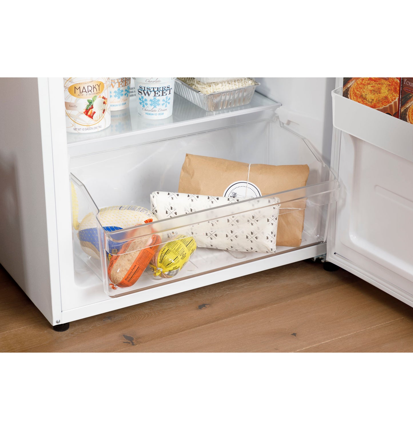 Clear freezer drawer with packaged frozen foods inside bottom compartment of upright freezer from appliances collection