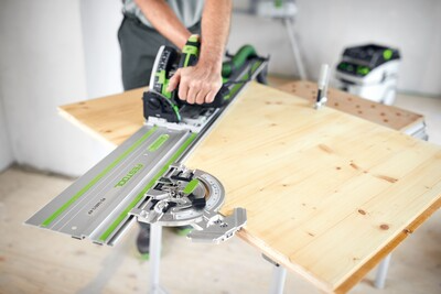 Close-up of a Festool guide rail and angle stop accessory being used on a light wood board in a woodworking workshop