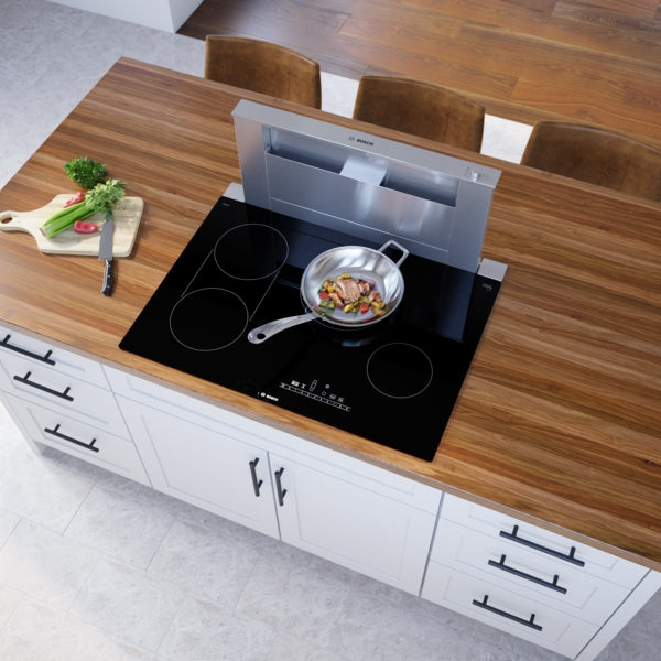 Black glass electric cooktop with four cooking zones and integrated downdraft ventilation in modern kitchen setting
