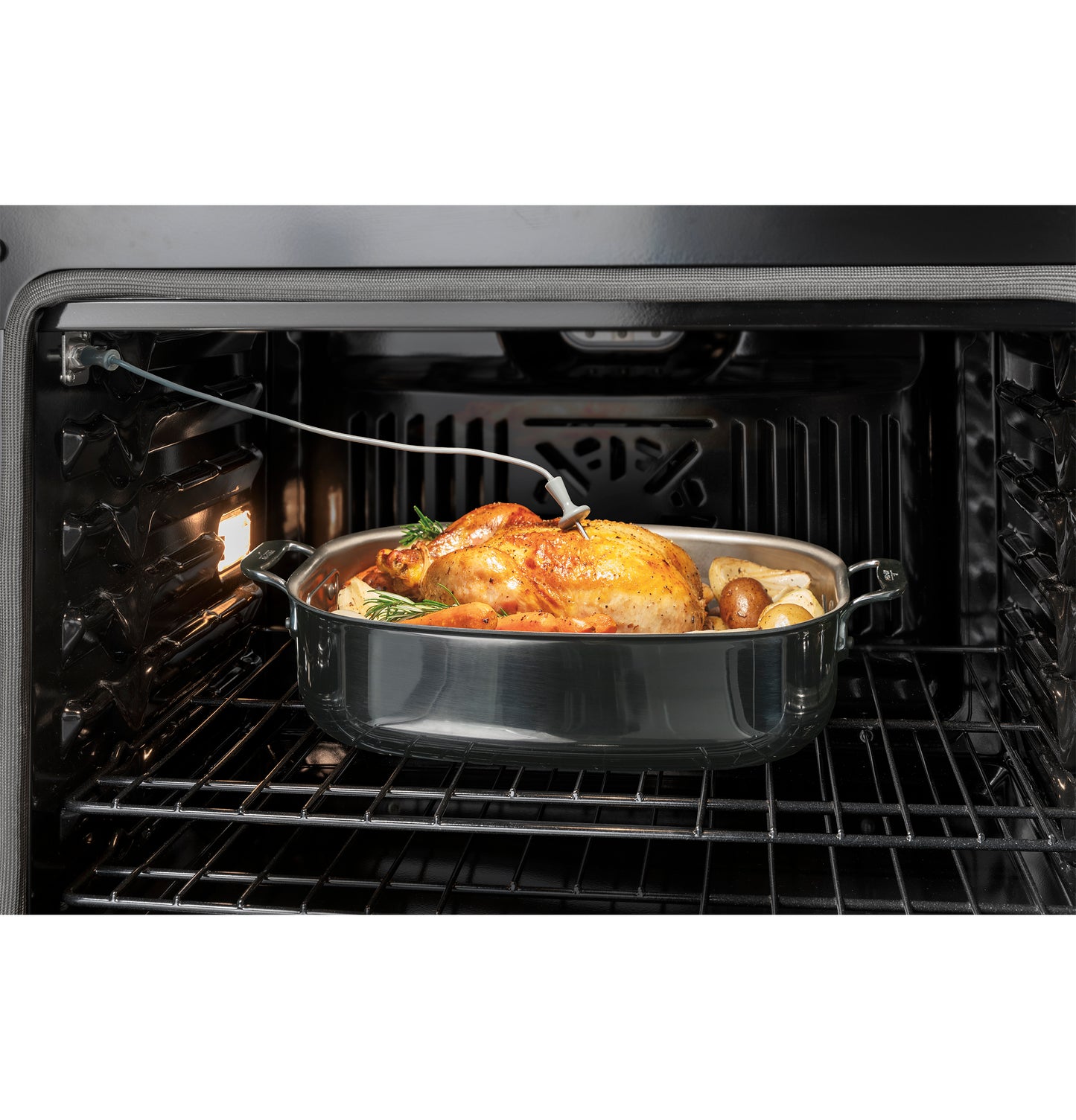 Golden brown roast chicken with vegetables cooking inside electric single wall oven from kitchen appliances collection