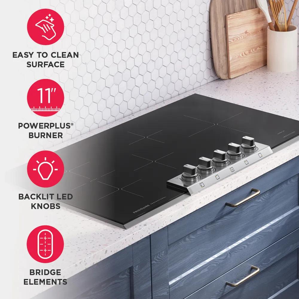 Black induction cooktop with backlit knobs and bridge elements installed on white quartz countertop in modern kitchen setting