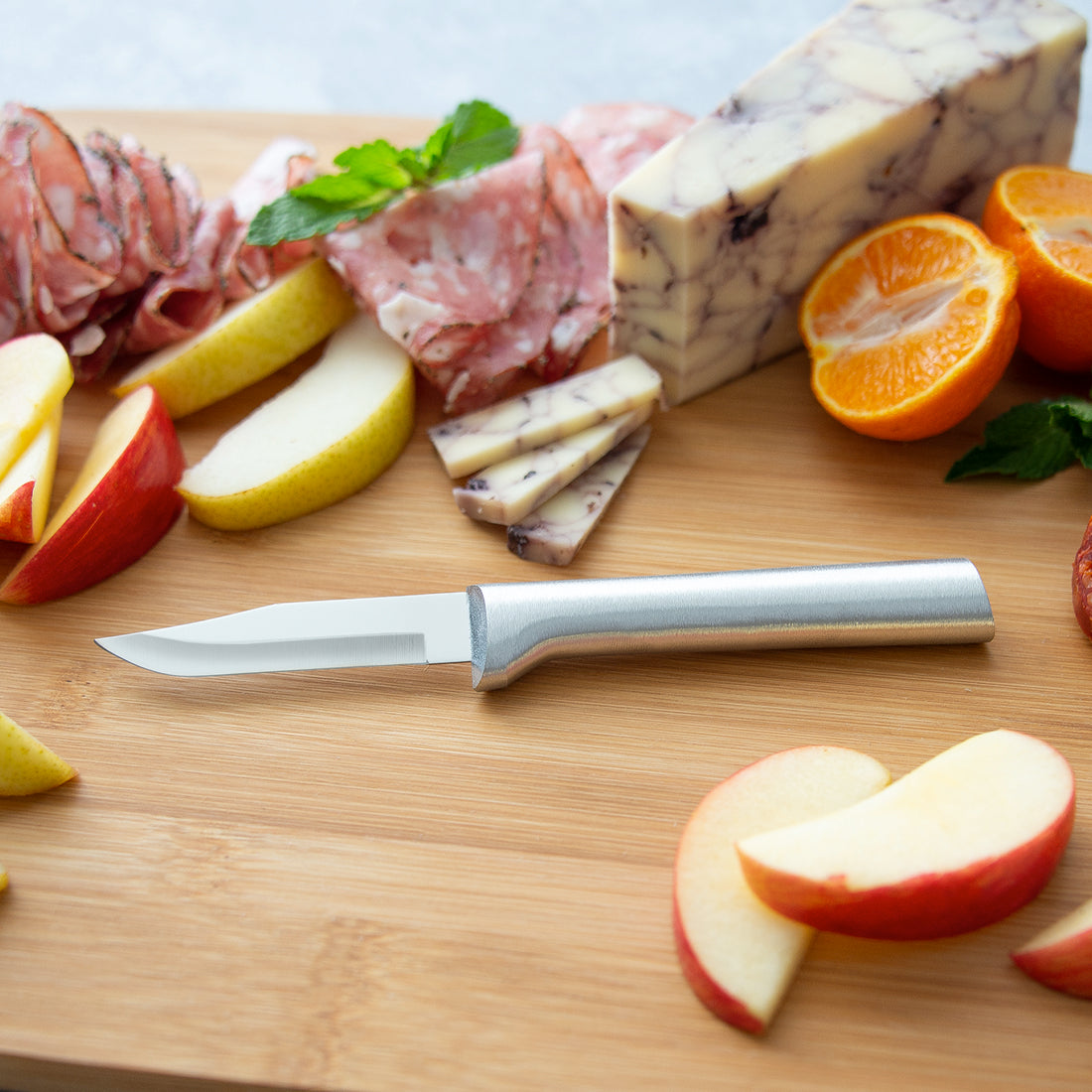 Rada paring knife with sleek cast aluminum handle cutting fruit and cheese on wooden board in Kitchenware collections