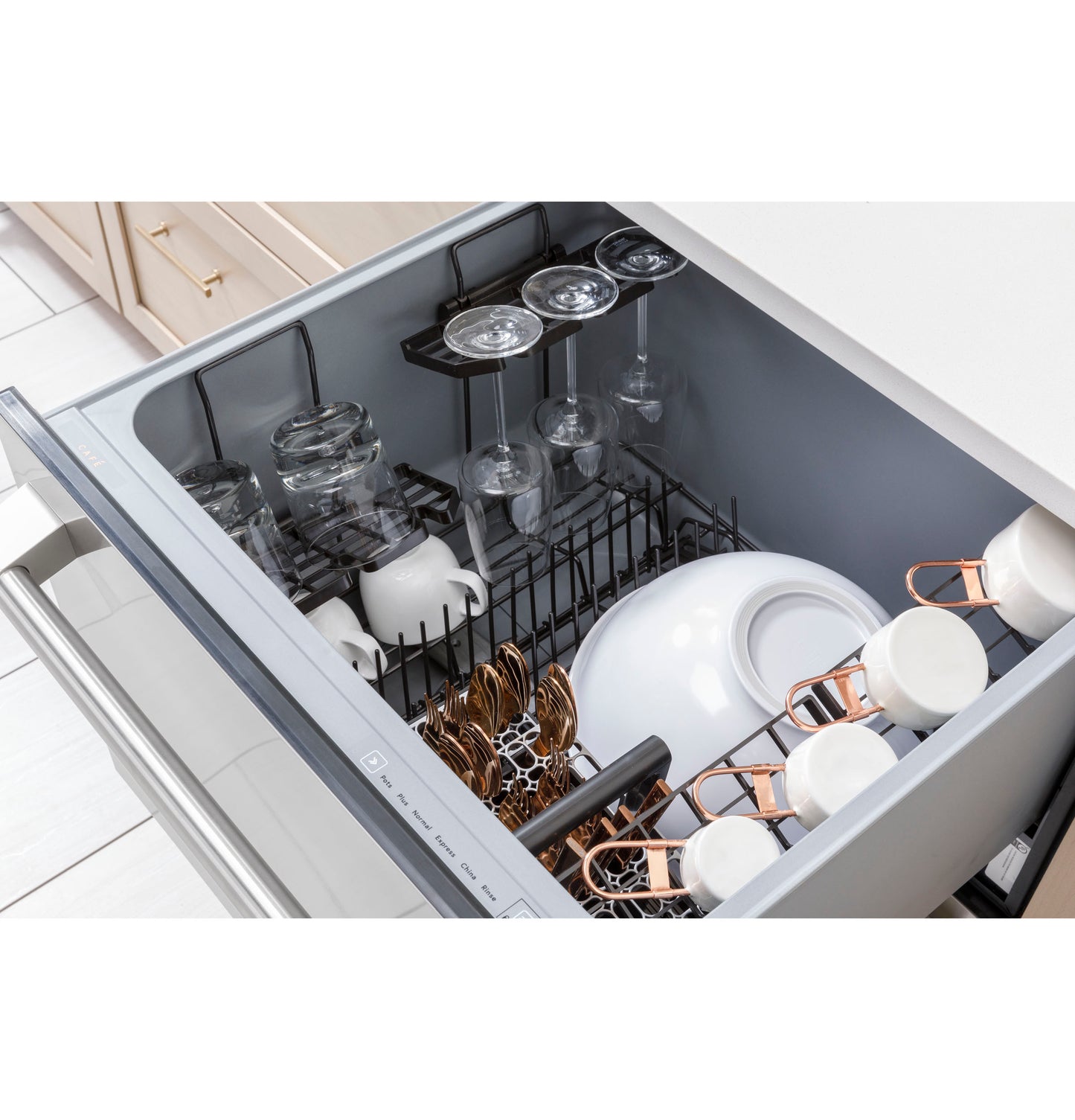 Open drawer dishwasher loaded with glasses, mugs, and white dishware in modern kitchen setting