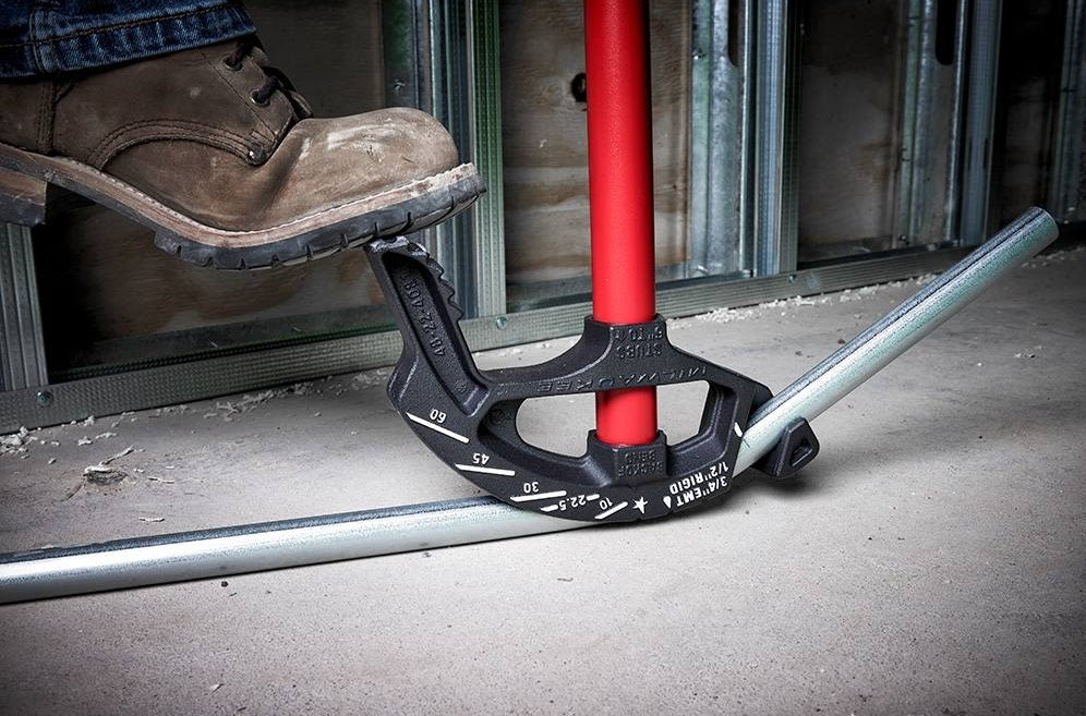 Milwaukee red-handled iron conduit bender bending 3/4 inch EMT pipe on concrete for electrical hand tools