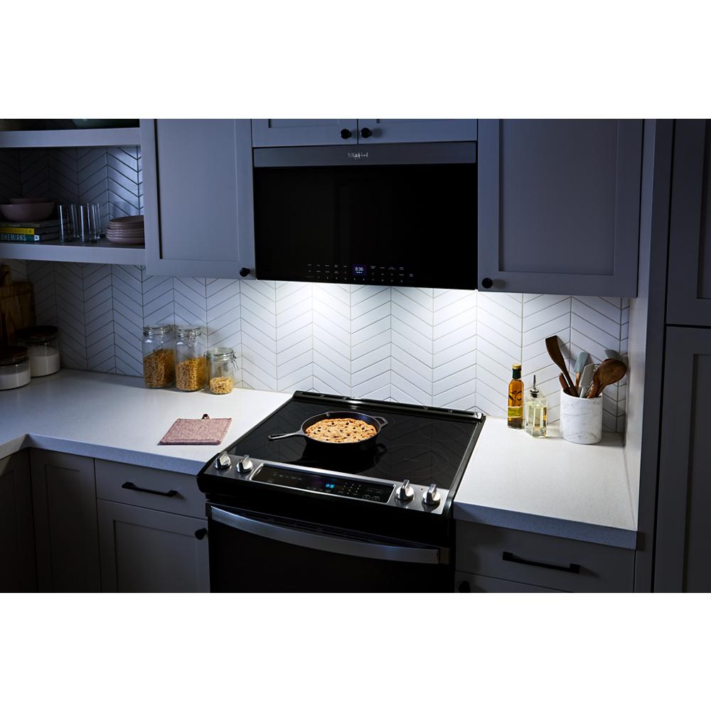 Modern kitchen with flush built-in oven and microwave in white cabinetry and chevron tile backsplash