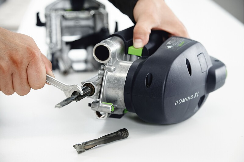 Person tightening or assembling a Festool Domino XL woodworking tool with wrench in power tool accessories collection