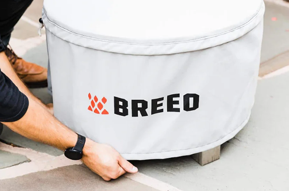 Light gray Breeo X30 fire pit cover with logo and adjustable fit for outdoor protection in home improvement settings