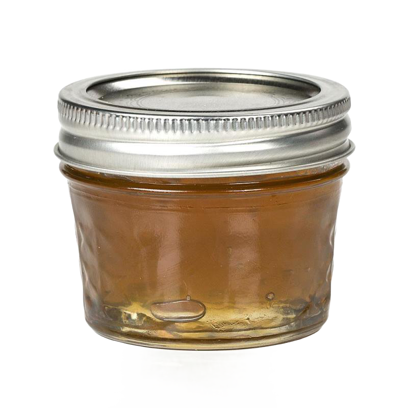 Small clear glass jar with metal lid containing orange jam, kitchenware item for home food storage and canning.