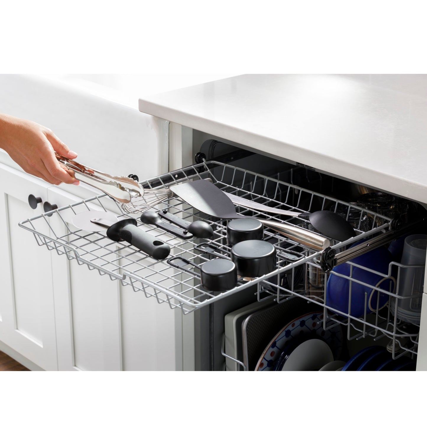 Loading large kitchen utensils and cookware into the top rack of a modern dishwasher in kitchen appliances collection