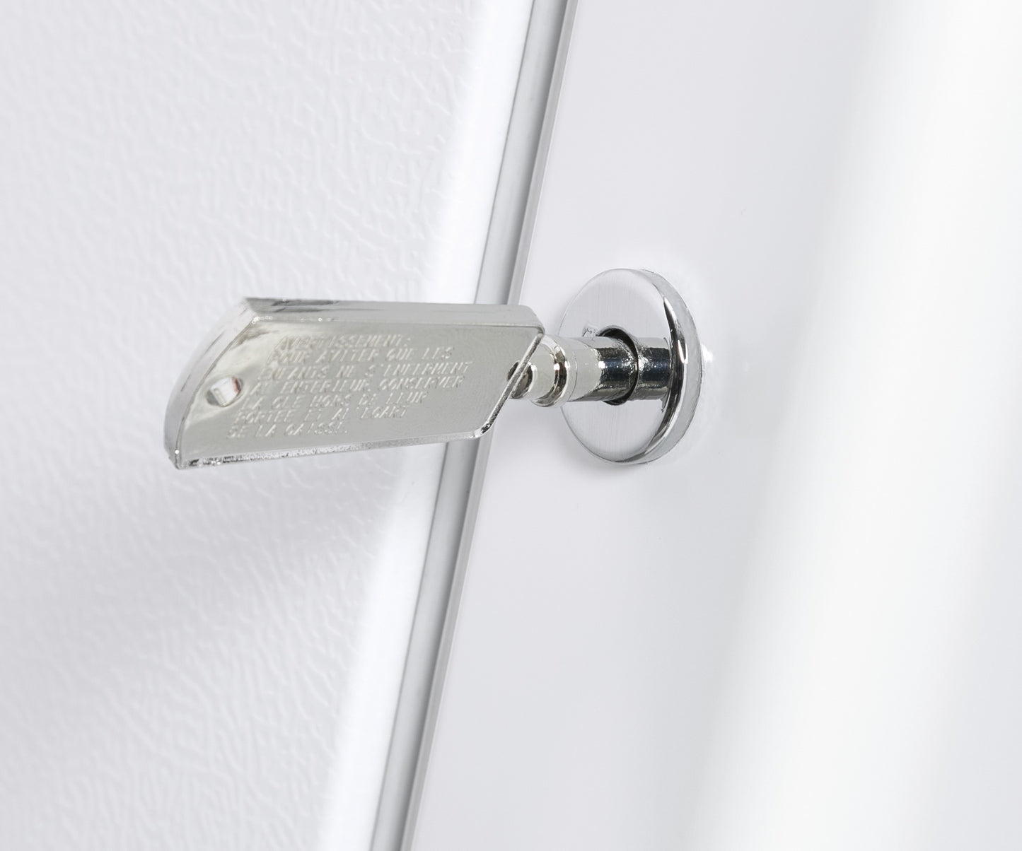 Close-up of a metal key inserted into the lock of a white upright freezer door in appliances collection