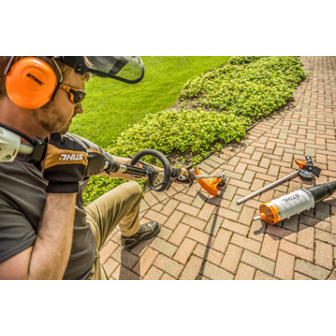 Man wearing protective gear using a STIHL KM 91 R KombiMotor for outdoor landscaping on a brick patio