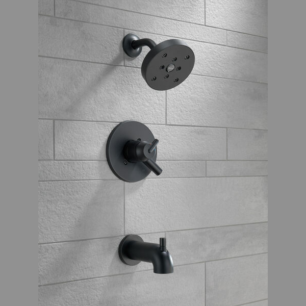 Matte black shower trim with wall-mounted round showerhead, single-handle valve, and tub spout in modern bathroom setting