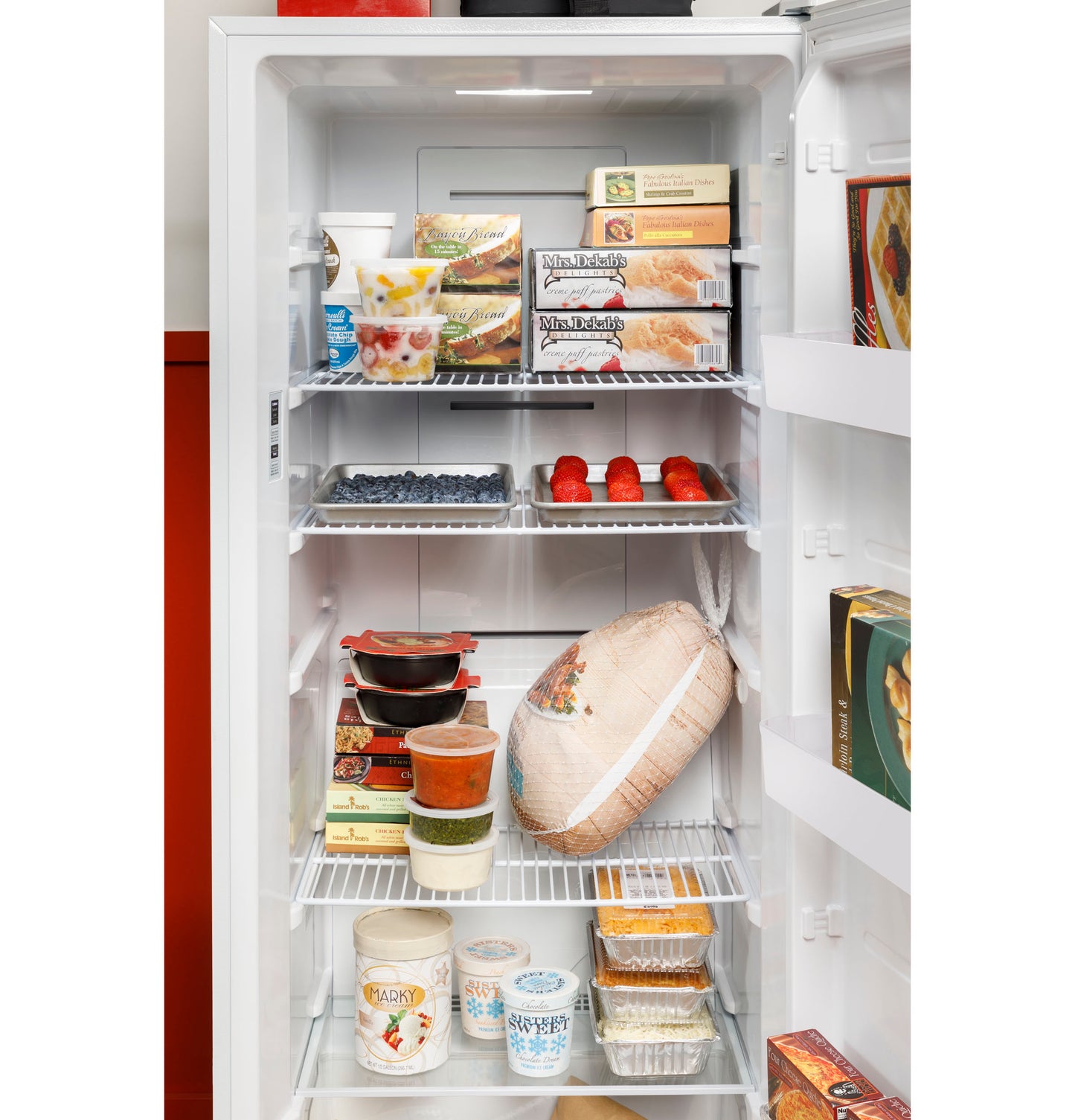 Open white upright freezer displaying organized frozen foods on wire shelves in kitchen appliance setting