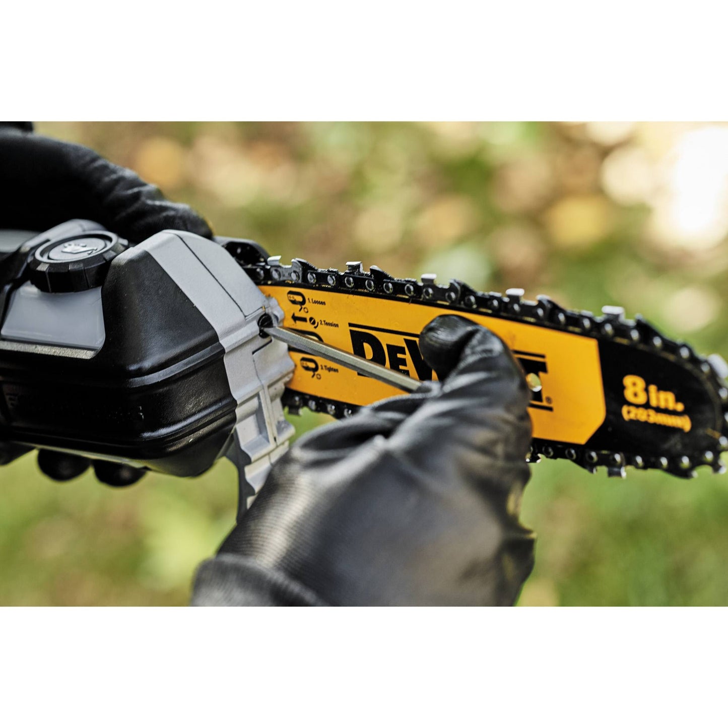 Close-up of hands wearing gloves adjusting the chain on an 8-inch cordless pole saw blade for outdoor tool use