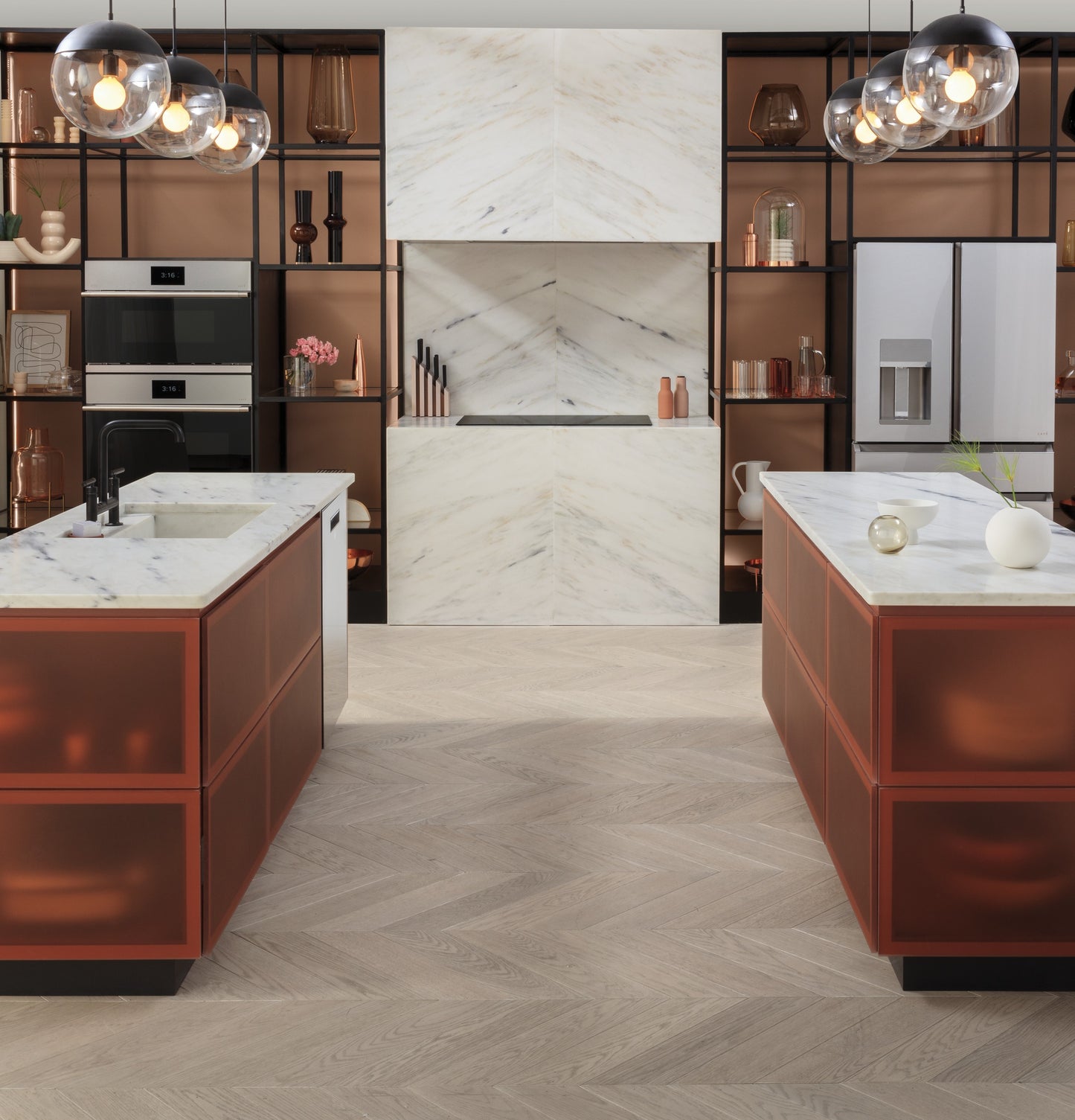 Contemporary kitchen with dual orange translucent islands, marble countertops, stainless steel appliances, and modern pendant lighting