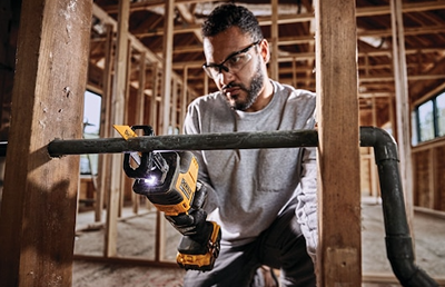 Man wearing safety glasses using DEWALT cordless one-handed reciprocating saw for home improvement cutting tasks