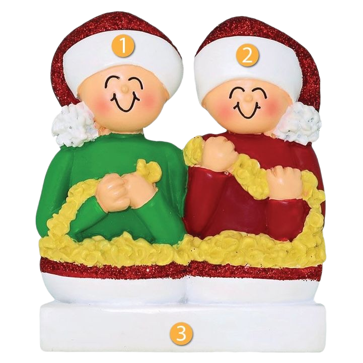 Festive couple ornament in red and green outfits stringing popcorn garland from Christmas decorations collection