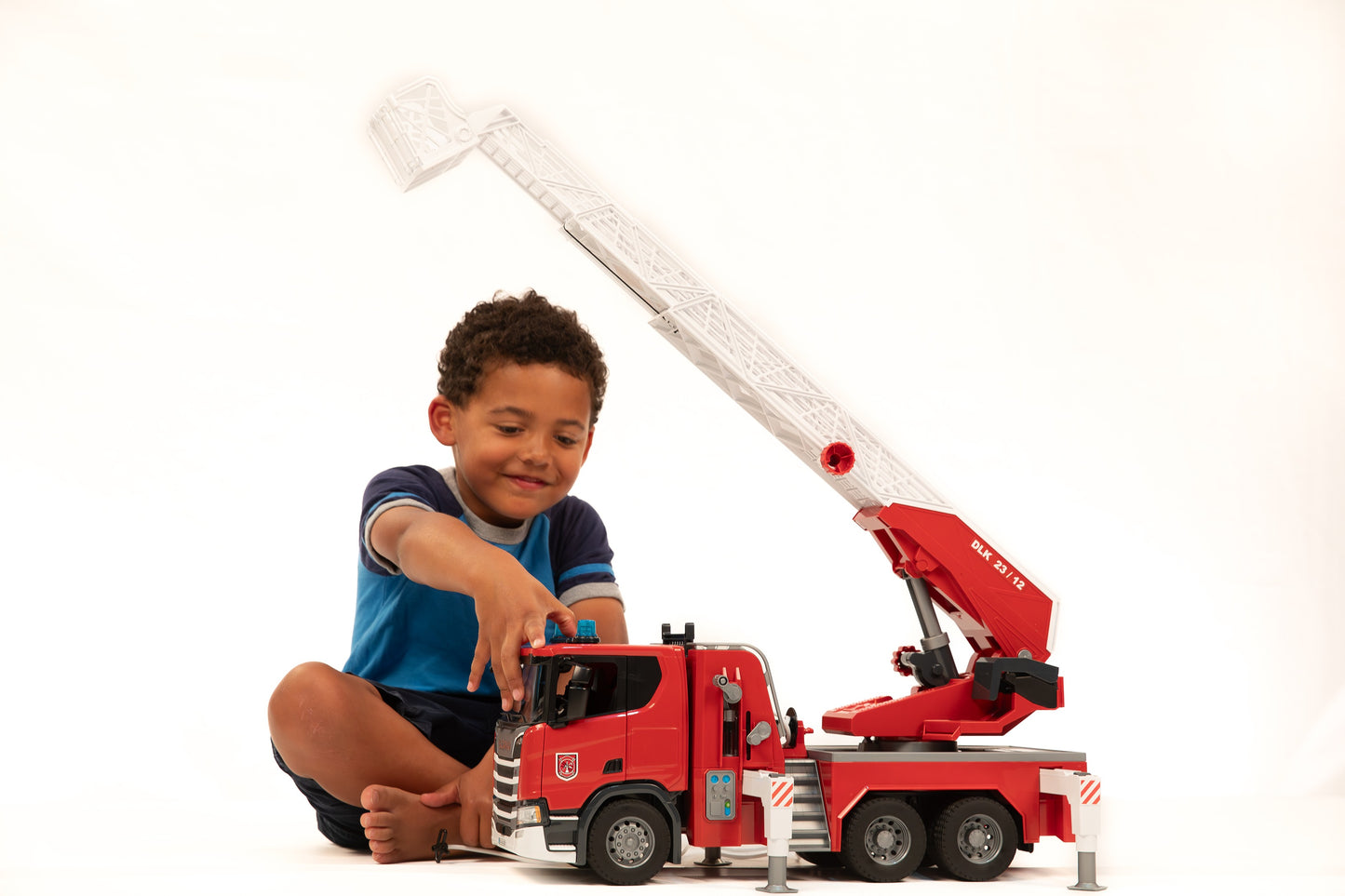 Young child playing with detailed red Bruder fire engine toy featuring extendable ladder from Bruder Toys collection